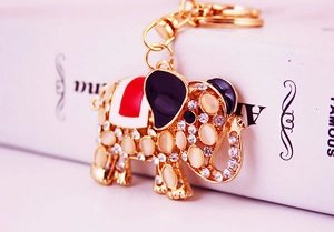 Macro view of golden elephant keychain featuring opal stones and enamel details on a book