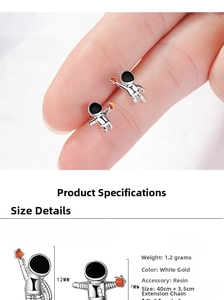 Detailed view of silver astronaut stud earrings with orange and black enamel finish