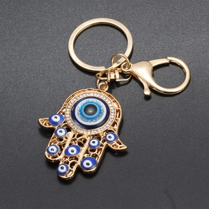 Close-up of golden Hamsa hand keychain with blue evil eye charms and sparkling rhinestones