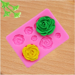 Pink silicone rose mold with finished green and yellow flower decorations on wood