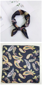 Detail of silk square scarf with paisley pattern tied in a bow and laid flat on table