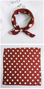 Detail of red silk scarf with white polka dots shown tied as a bow and laid flat