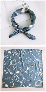 Detail of silk scarf with gold chain and jewel patterns on deep teal background