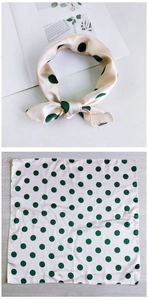 Detail of beige and green polka dot silk scarf tied as a bow and laid flat