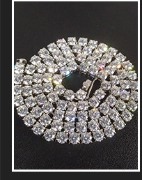 Macro view of 4mm silver tennis necklace with sparkling cubic zirconia on black background