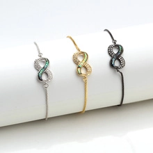 Detailed view of infinity charm bracelets with opal and diamonds in silver, gold and black