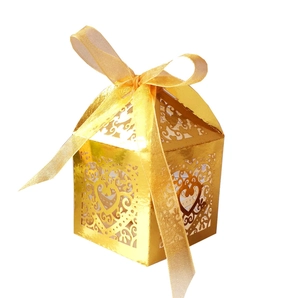 Golden laser-cut heart favor box with intricate vine patterns and matching silk ribbon