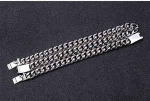 Three silver stainless steel Cuban link chains in different widths on dark texture