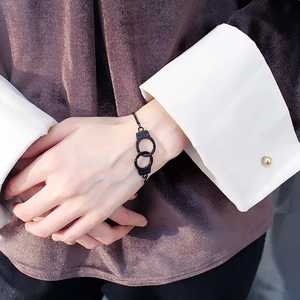 Detail of black handcuff bracelet with FREEDOM engraving worn on a model's wrist