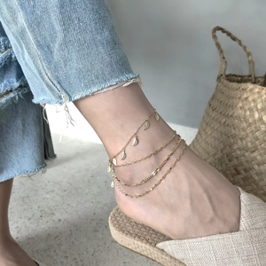 Bohemian gold layered anklet with delicate leaf pendants worn for a casual summer look