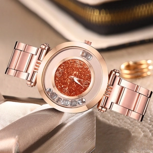 Detailed close-up of a rose gold watch featuring a sparkling orange glitter dial with rhinestones