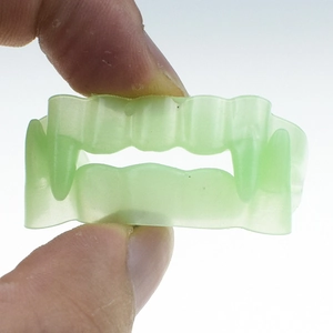 Close-up of flexible light green glow-in-the-dark vampire fangs for Halloween props
