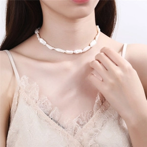 Baroque irregular white pearl choker necklace styled with a beige lace trim top