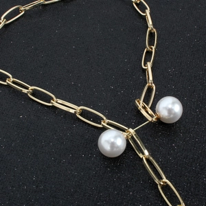 Close-up of elegant gold chain with lustrous white pearls on a dark background