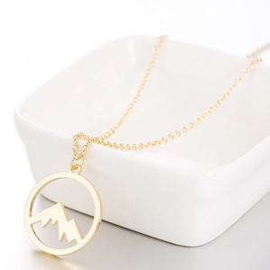 Elegant gold hollow mountain peak pendant necklace displayed in a white ceramic dish
