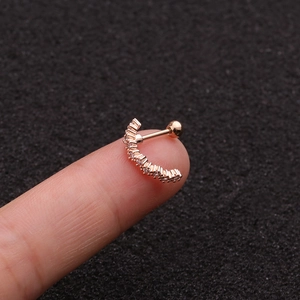 Detail of rose gold curved cartilage stud earring with tiny zircons held on a fingertip