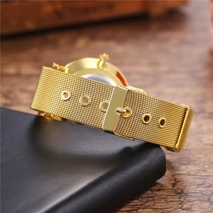 Macro view of gold mesh watch strap with pin buckle and textured stainless steel weaving