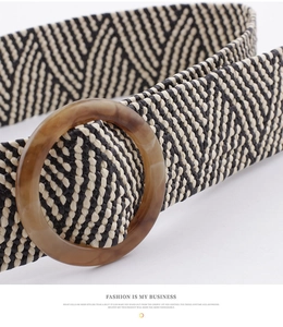 Close-up of black and white chevron woven belt with round amber resin buckle detail