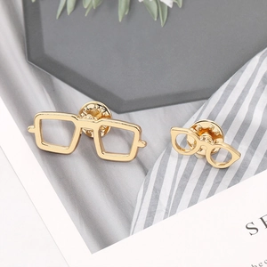 Detail of gold-tone metal eyewear-shaped lapel pins with secure butterfly clasp closure