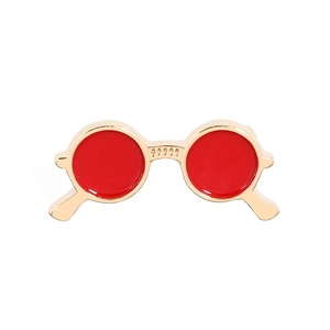 Detail of creative red round sunglasses brooch with golden metal frame and enamel finish