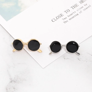 Detail of creative gold and silver sunglasses-shaped brooches on marble surface