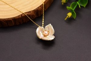 Macro detail of 925 silver flower necklace with pink pearl and golden petal accents