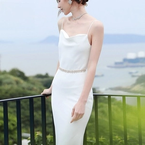 Detail of sunflower rhinestone belt with ribbon on white bridal dress with sea view
