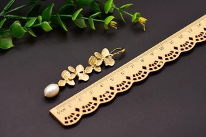 Detail view of gold flower petal earrings with pearl and scale ruler showing 6cm length