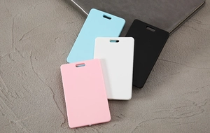 Blank ABS plastic card holders in blue, black, white, and pink on stone surface
