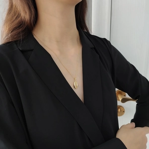 Close-up of a gold shell pendant necklace worn by a model in professional black attire