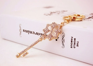 Close-up of golden four-leaf clover key pendant with rhinestones on a white book