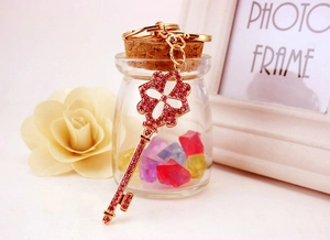 Detailed shot of pink rhinestone four-leaf clover key pendant on a glass bottle