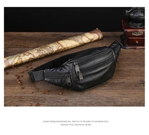 Close-up of black leather fanny pack with multi-zipper design on vintage wood desk