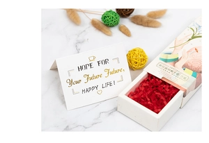 Close-up of orchid hand cream gift box with white greeting card on marble background