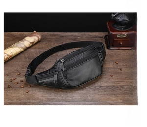 Close-up of black leather waist bag with zipper detail on a vintage wooden desk background