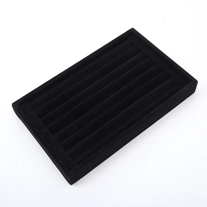 Close-up of black velvet jewelry display tray with multiple slots for rings and studs