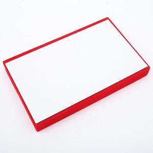 Close-up of a small velvet jewelry display tray with a red frame and white interior