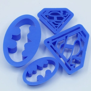 Detail view of four blue plastic superhero logo cookie cutters for cake decorating