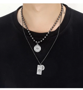 Detail of hiphop double-layer bead necklace with engraved silver pendant charms