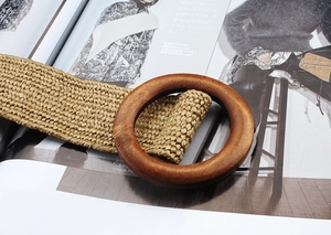 Close-up of woven straw belt with a large circular wooden buckle on a fashion magazine