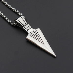 Detailed close-up of a silver arrow pendant necklace with textured grid pattern engraving