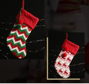 Detailed view of knitted Christmas stockings with reindeer patterns and plush pom-poms