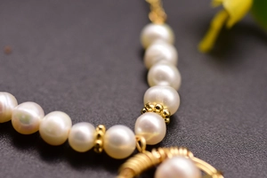 Macro shot of natural freshwater pearls and handcrafted gold wire-wrapped pendant detail