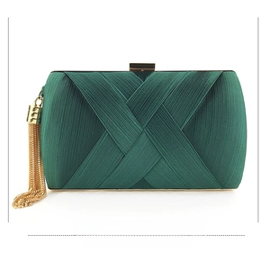 Detail of dark green satin evening clutch with elegant pleats and gold tassel charm