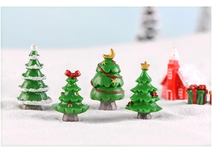 Macro shot of four mini green Christmas trees with snow and festive ornaments on white snow