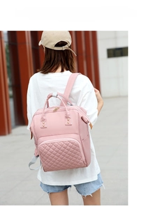 Outdoor shot of a pink nylon maternity backpack with quilted detail and dual straps