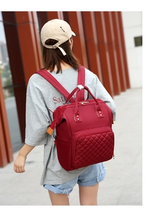 Outdoor view of large dark red nylon backpack with quilted front pocket and metal zipper