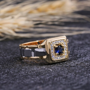 Detail of square gold and gunmetal ring featuring a deep blue stone and zircon accents