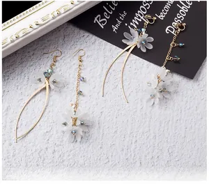 Detailed close-up of white shell flower earrings with blue crystal and gold chain