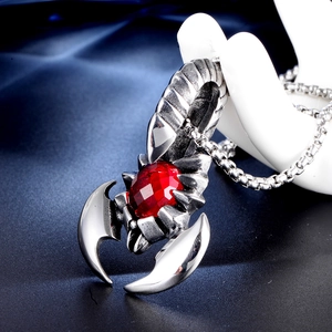 Macro shot of silver scorpion pendant with red ruby stone on white hand display
